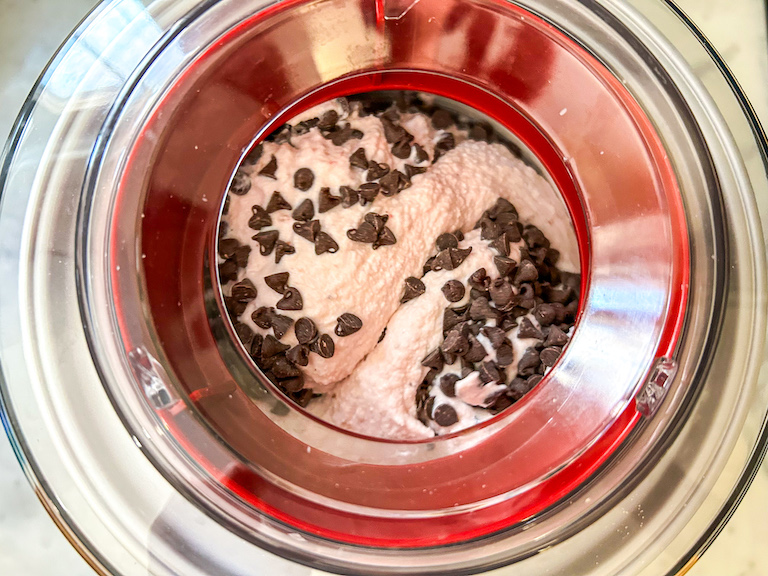 Ice cream maker churning strawberry ice cream with miniature chocolate chips