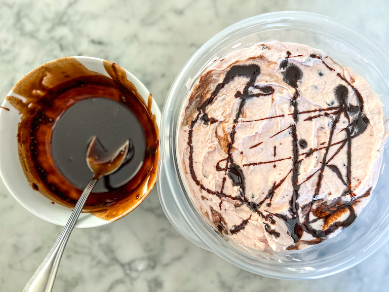 Bowl of chocolate sauce and container of strawberry ice cream