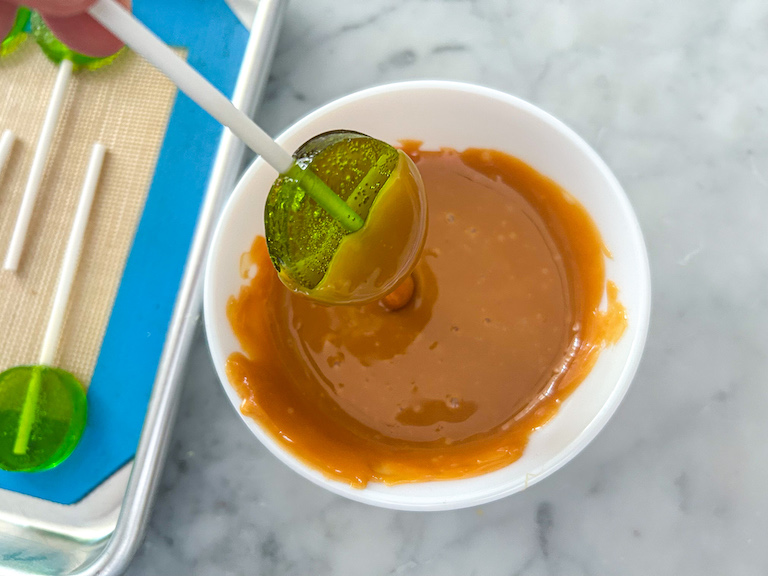 Dipping a lollipop in melted caramel