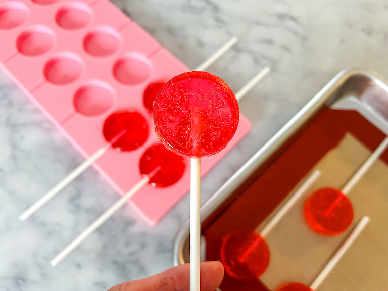 Hand holding a watermelon lollipop