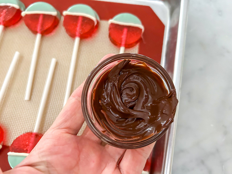 Hand holding small dish of melted chocolate