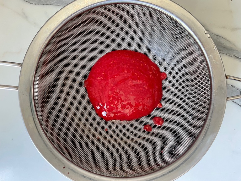 Raspberry puree in a mesh strainer