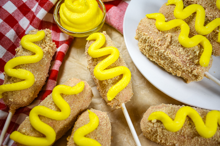 Corn dog cake pops and red checkered towels on a sheet of parchment