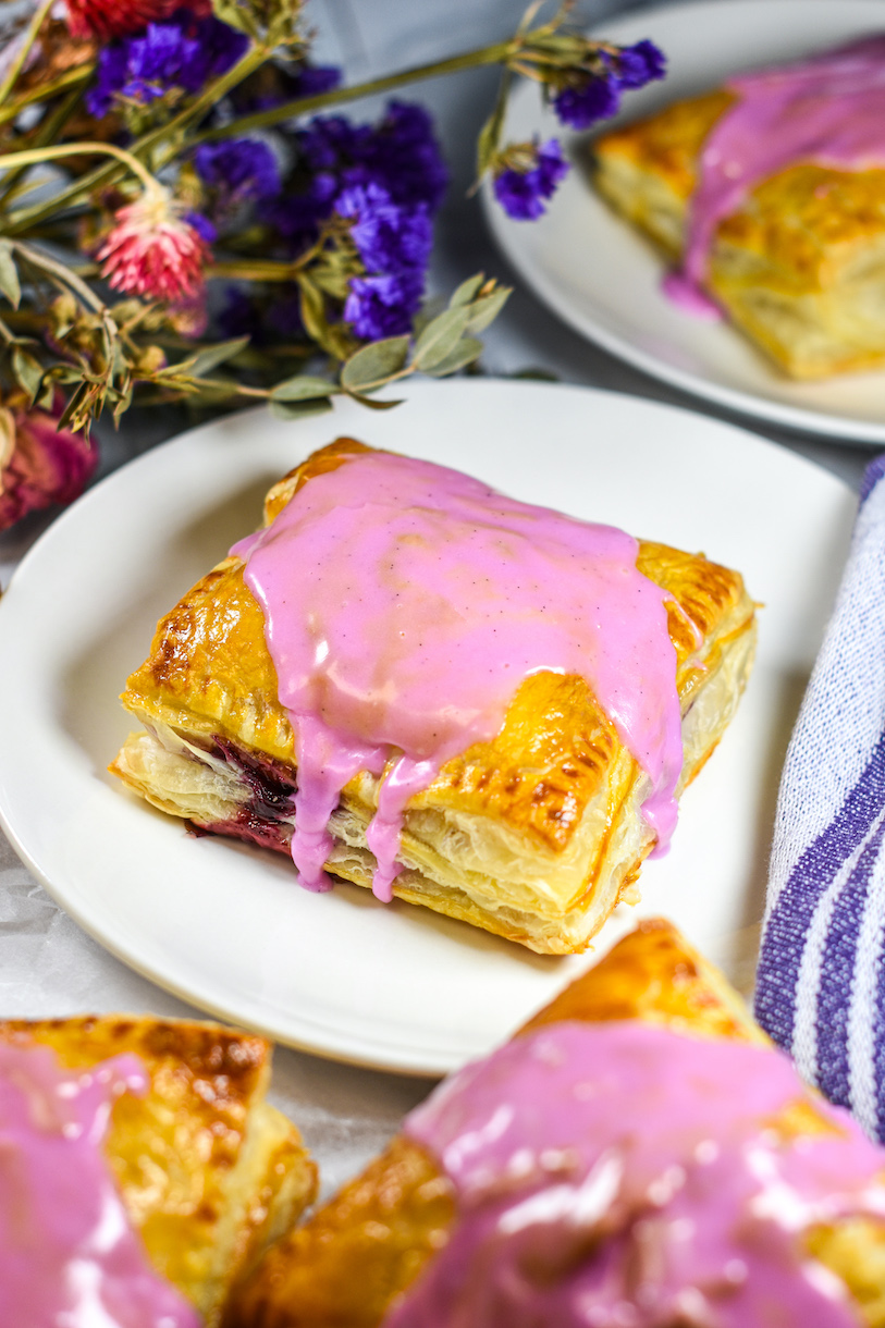 Mixed berry hand pie on a plate with purple flowers