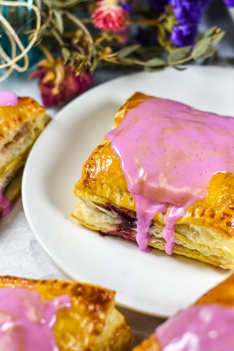 Puff pastry hand pie with purple glaze dripping down the side