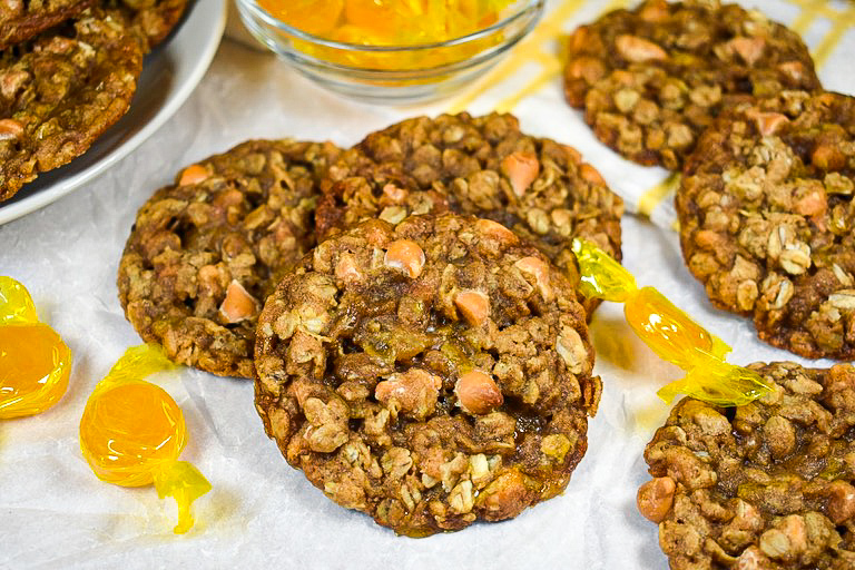 Oatmeal cookies and butterscotch candies on a white surface