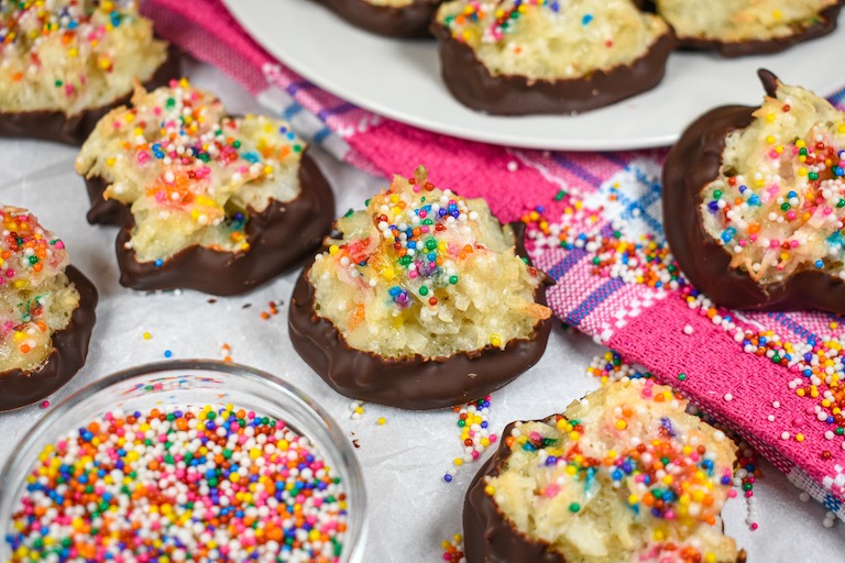 Birthday cake macaroons and a dish of sprinkles on a pink towel