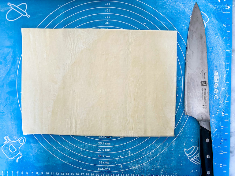 rectangle of puff pastry on a rolling mat with a knife