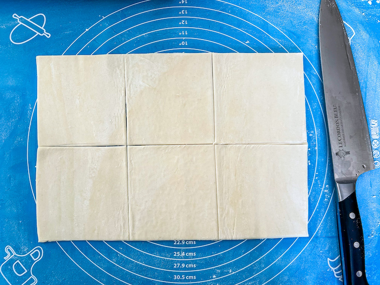 knife cutting puff pastry into squares