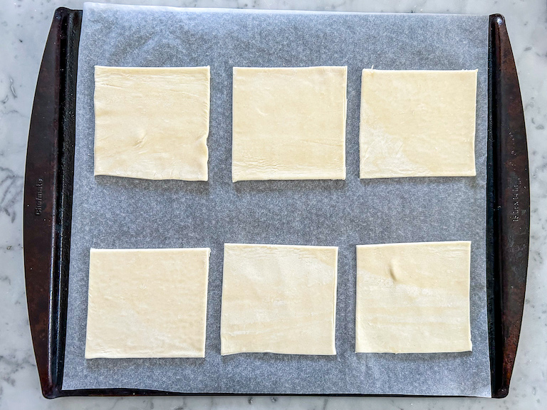 six squares of puff pastry on a tray