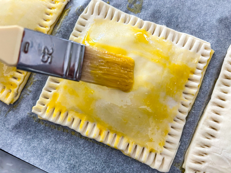 Brushing egg wash over puff pastry hand pie