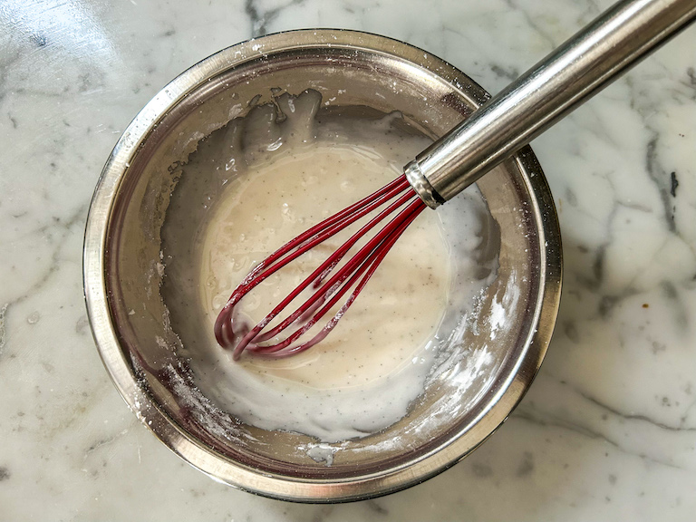 Vanilla bean glaze in a bowl with a whisk