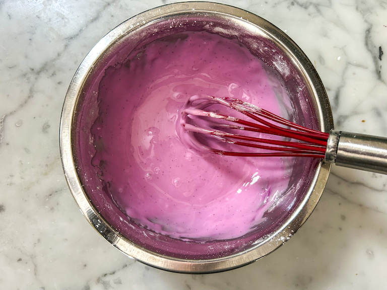 A bowl of purple glaze with a whisk