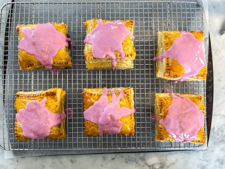 Berry hand pies on a wire rack with vanilla bean glaze