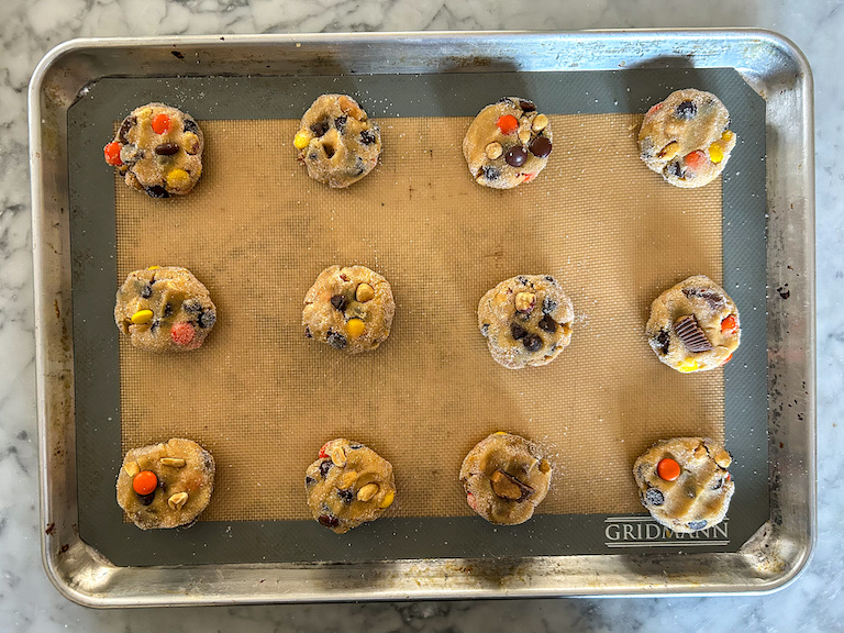 Pressing additional Reese's Pieces and peanut butter cups into the tops of balls of cookie dough