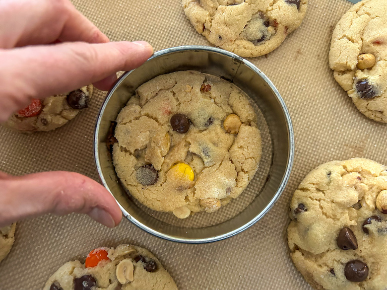 hand reshaping a cookie with a round cutter