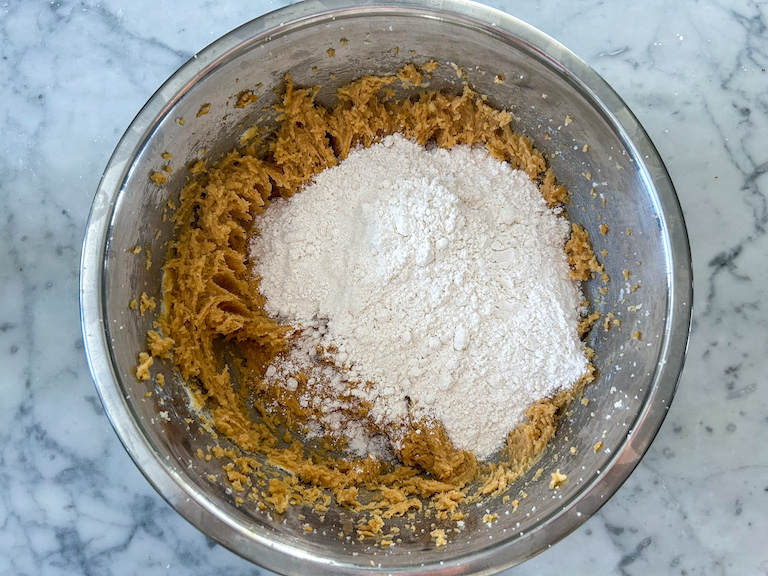 Adding dry ingredients to peanut butter cookie dough