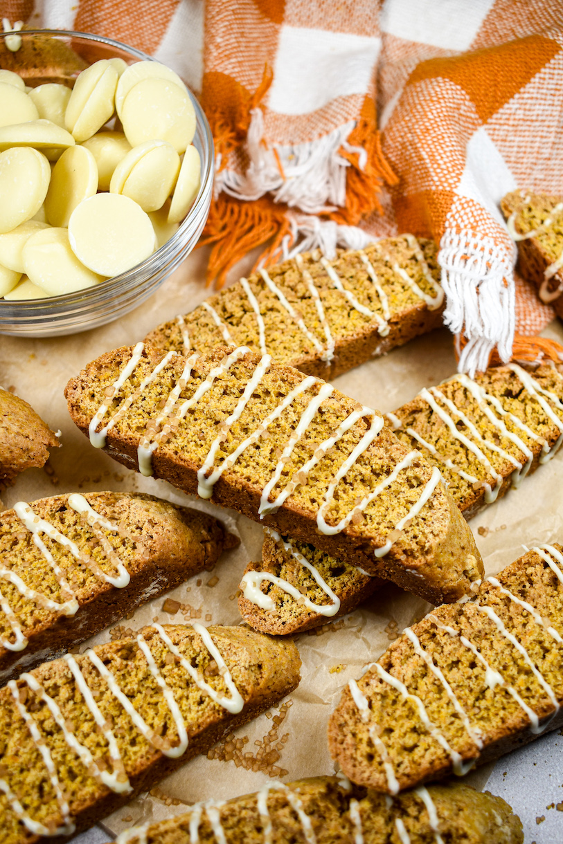 A bowl of white chocolate, orange tea towel, and pumpkin biscotti cookies