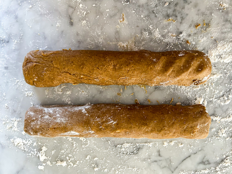 Two logs of pumpkin biscotti dough on a floured countertop