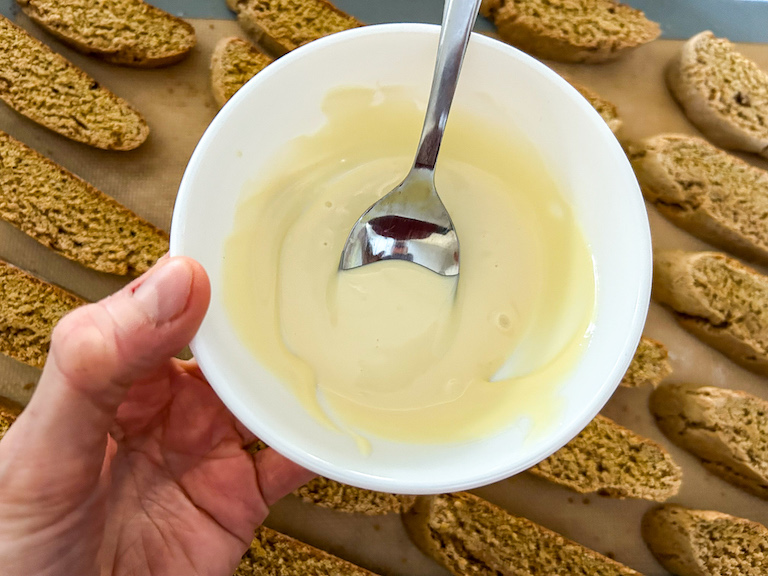 Hand holding a dish of melted white chocolate