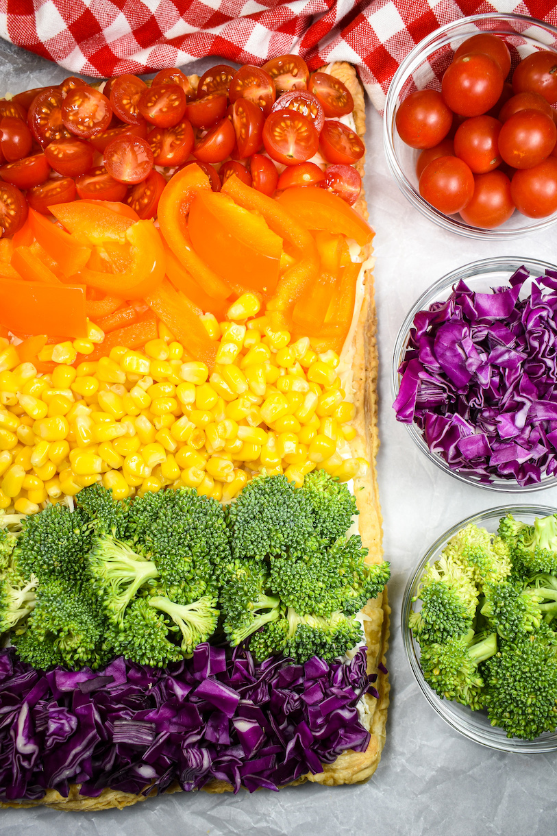 rainbow pizza with dishes of colorful raw vegetables