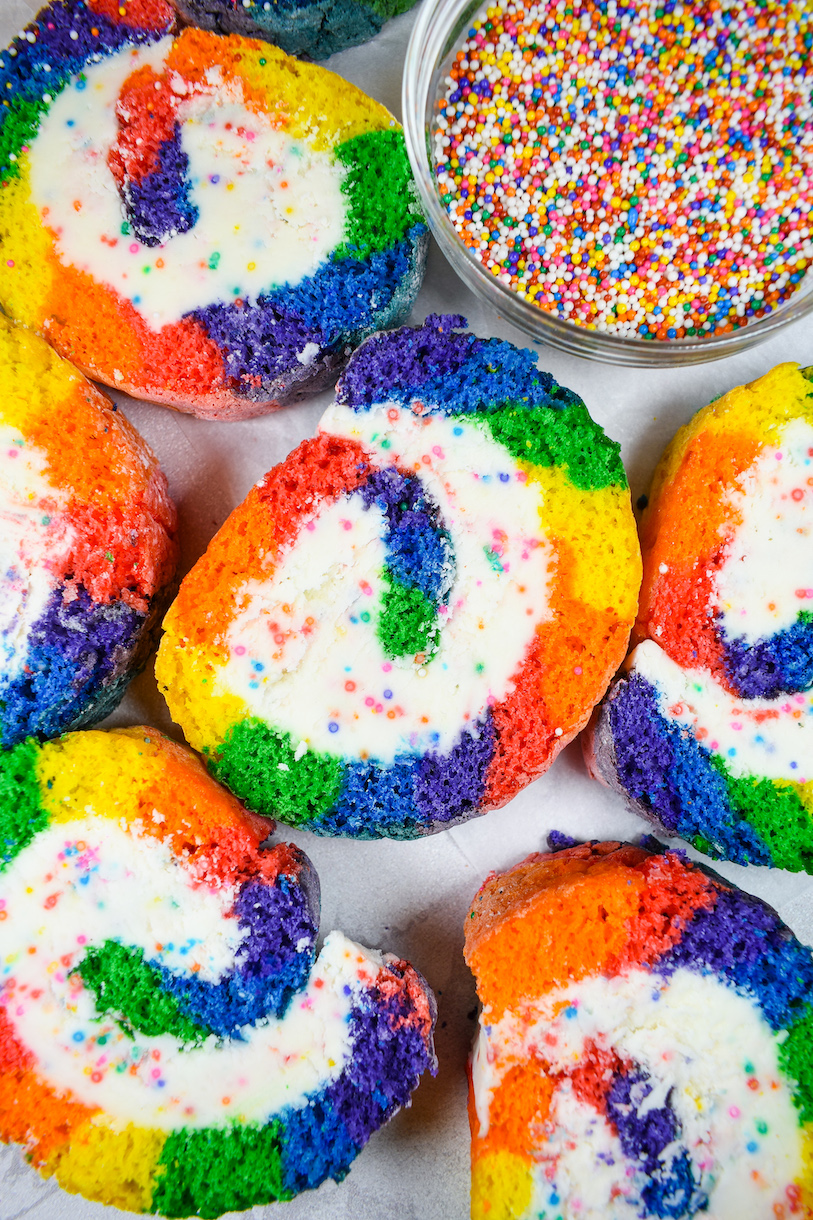 slices of rainbow cake roll on a white surface