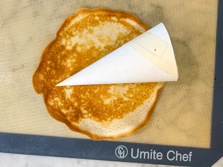 Rolling ice cream cone batter around a cardboard template