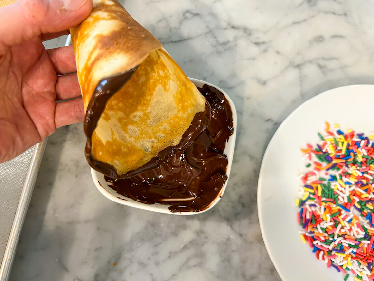 Hand dipping homemade icecream cone in melted chocolate