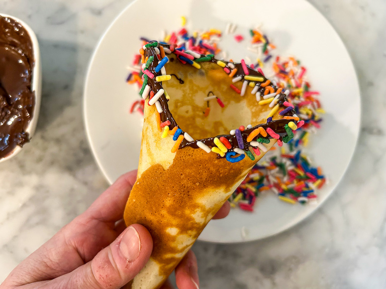 Homemade chocolate dipped ice cream cone with rainbow sprinkles