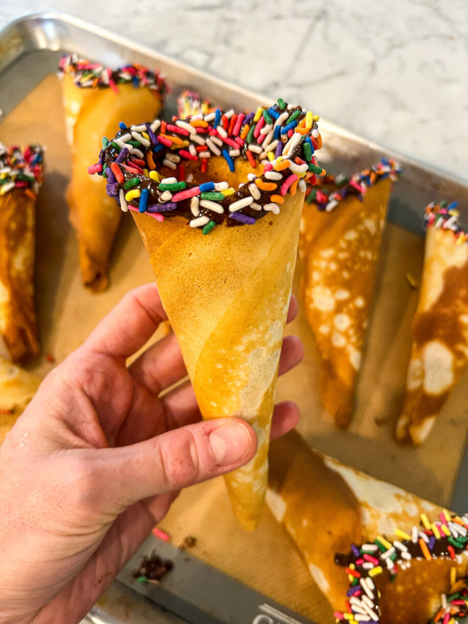 Hand holding a homemade ice cream cone with rainbow sprinkles
