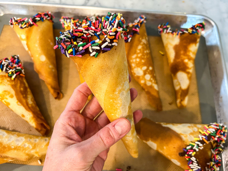Hand holding a chocolate dipped ice cream cone with sprinkles