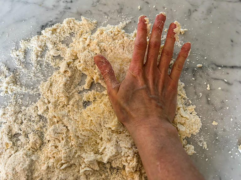 Hand blending pastry on a marble countertop