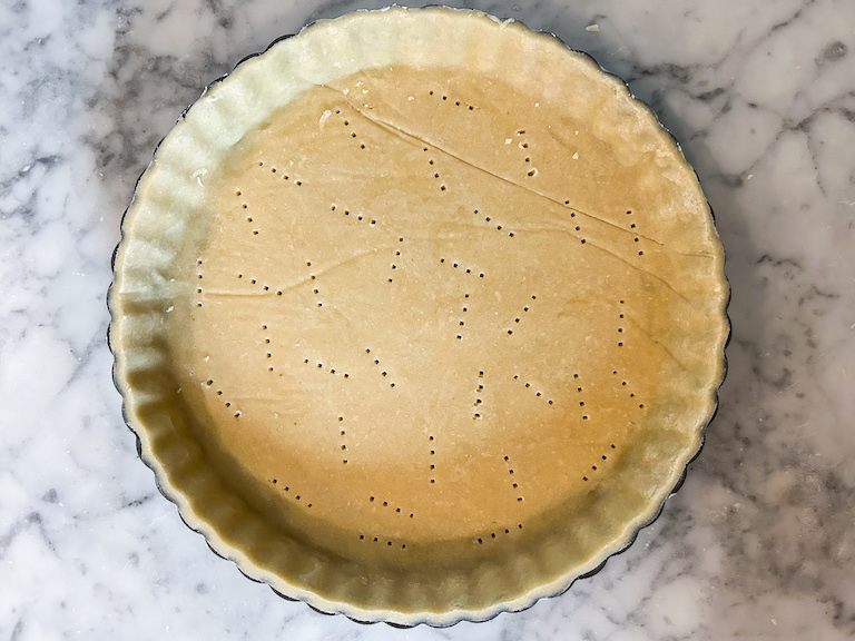Fluted tart tin lined with sweet pastry and docked with a fork