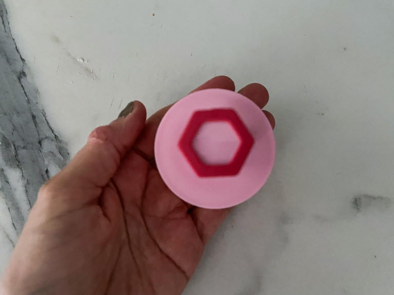 Hand holding a pink round biscuit cutter