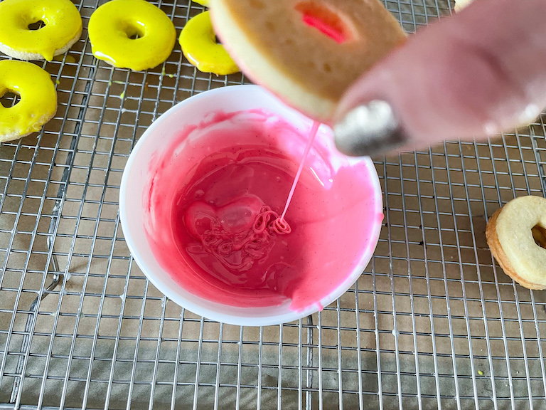 Hand dipping a cookie in pink icing