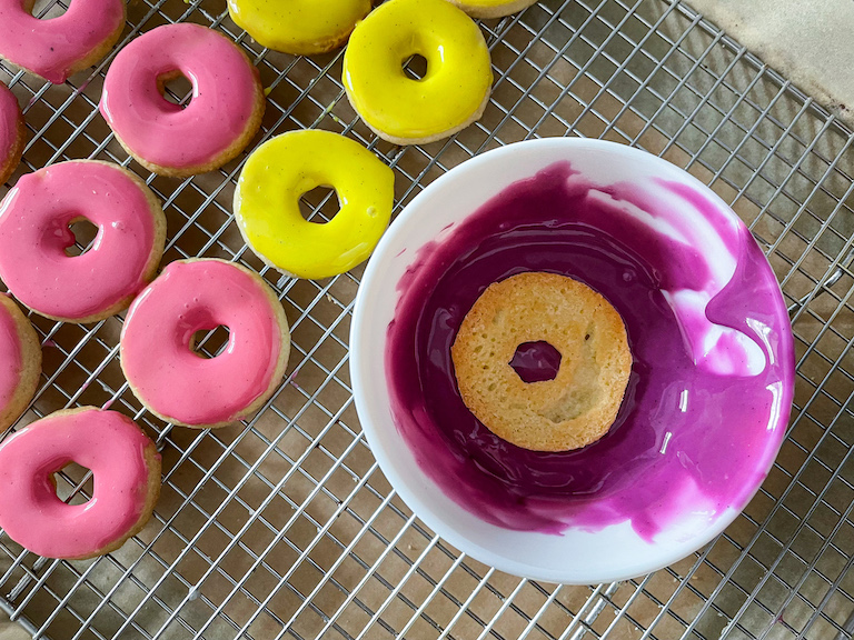 Dunking a ring shaped cookie in purple icing