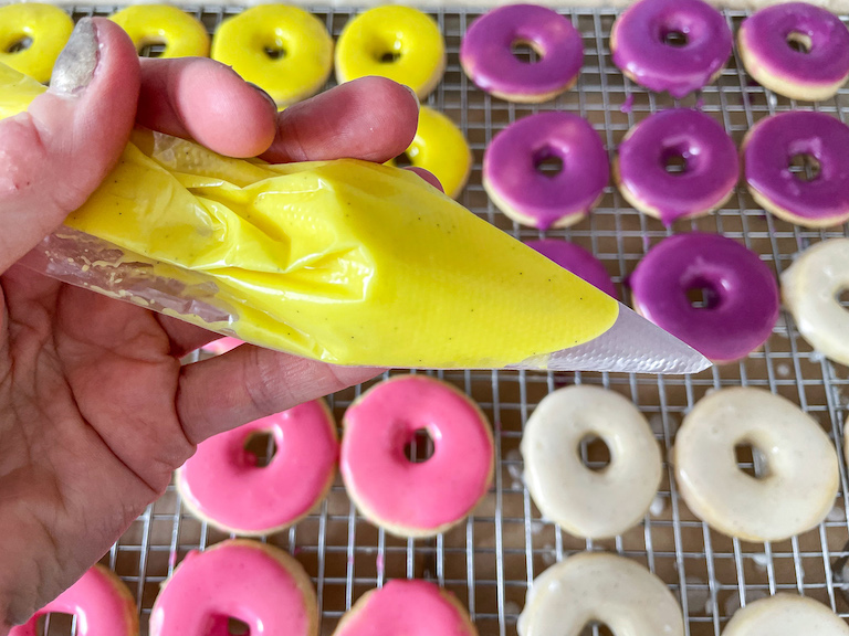 Hand holding a piping bag of yellow icing