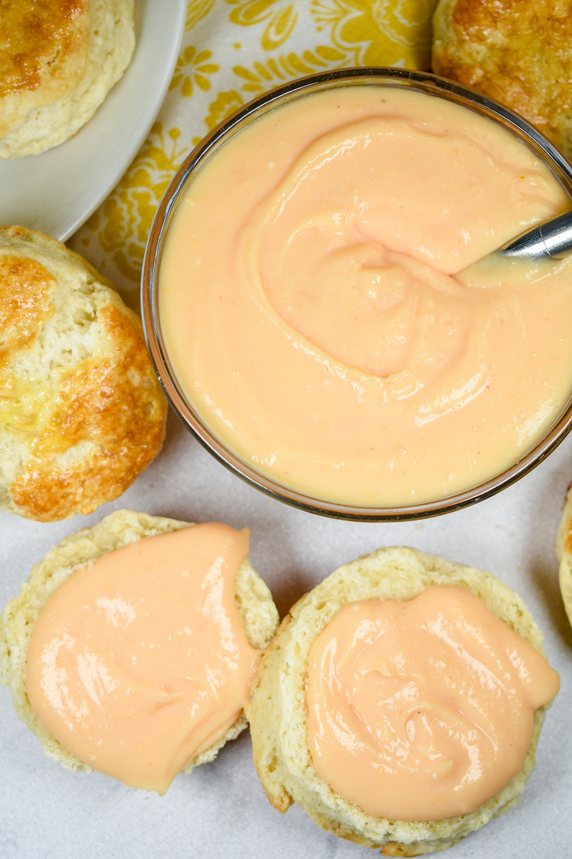 A bowl of grapefruit curd surrounded by homemade scones