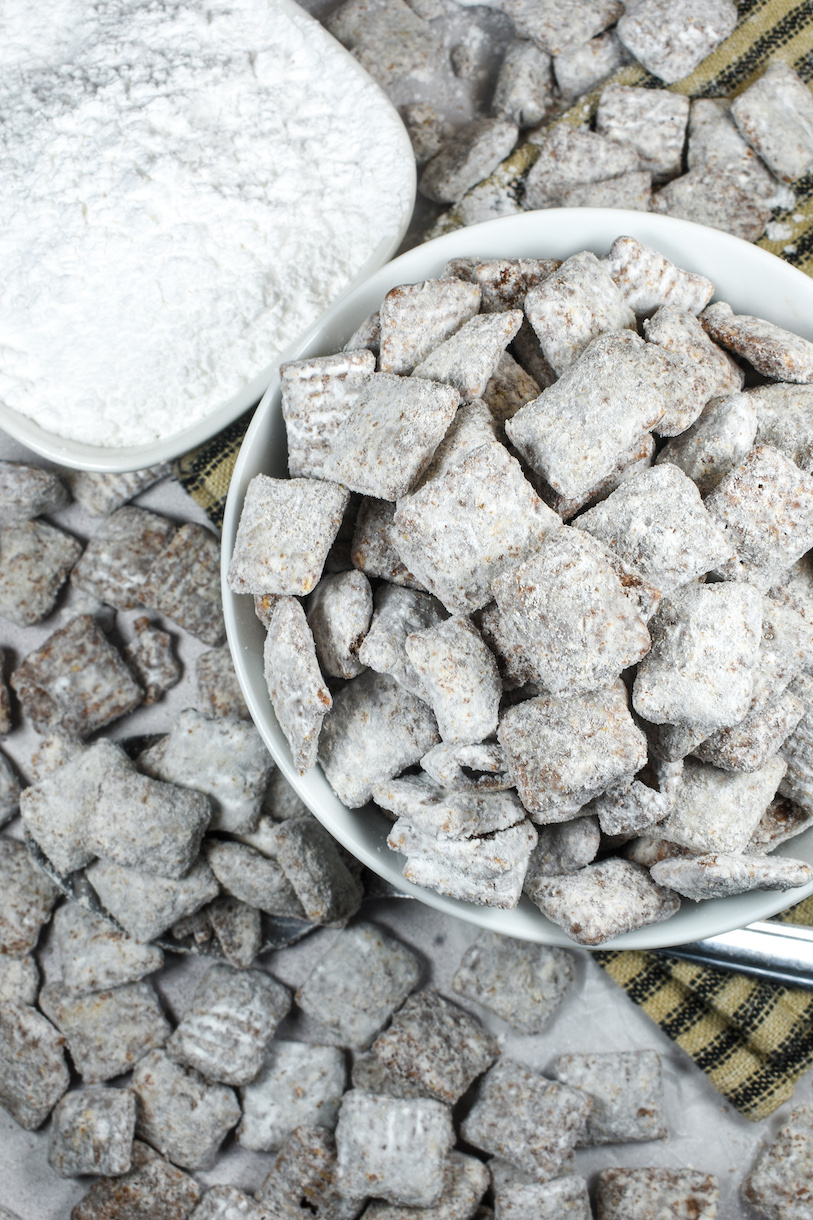 a bowl of puppy chow, a dish of confectioner's sugar, and a spoon