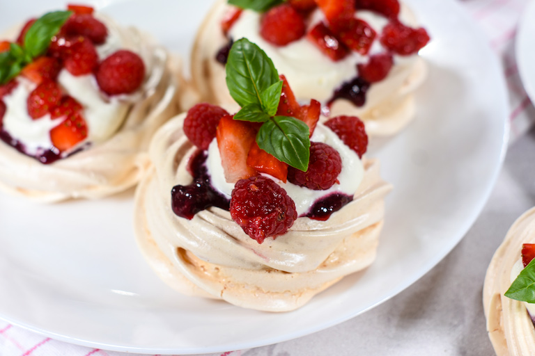 Mini pavlovas decorated with whipped cream and berries