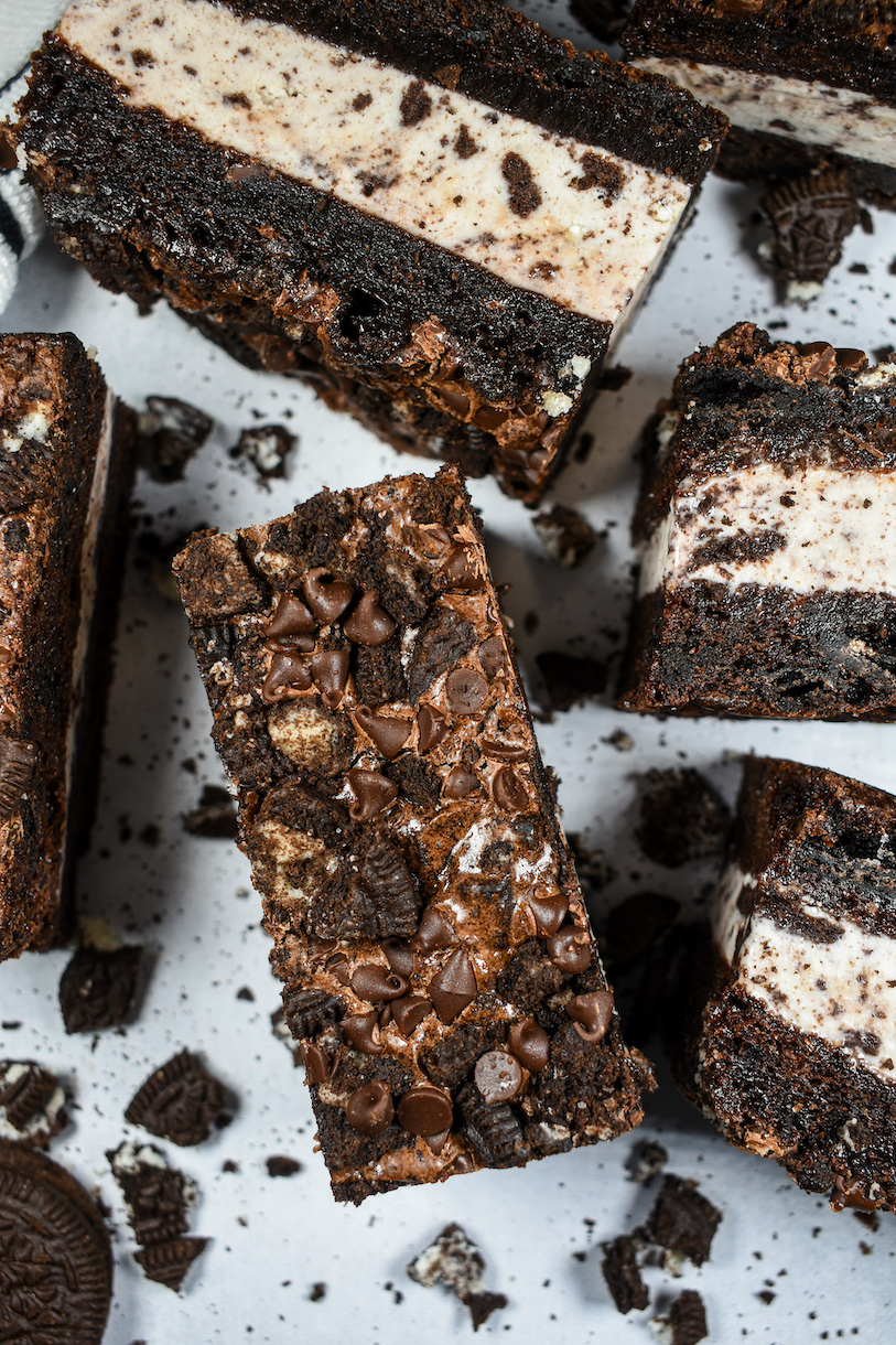 Oreo brownie ice cream sandwiches arranged on a white surface with crushed Oreo cookies