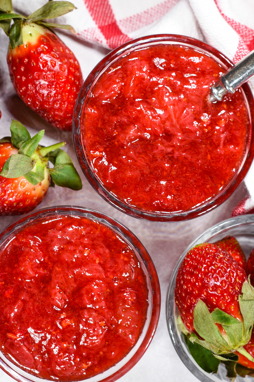 Dishes of strawberry compote surrounded by fresh berries