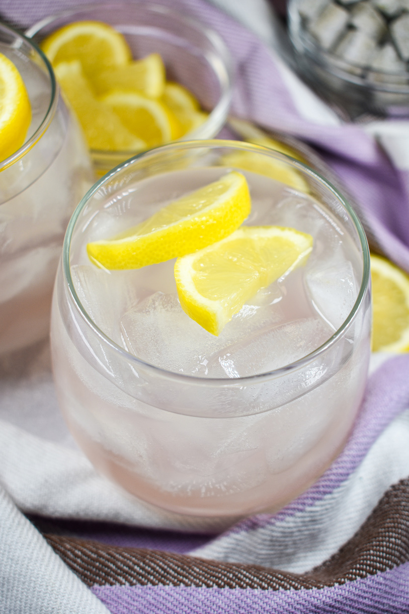 A glass of lavender lemonade garnished with lemon slices