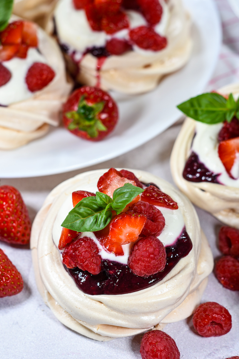 Individual pavlova with compote, cream, and berries
