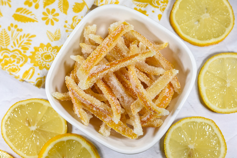 A dish of candied lemon peels surrounded by lemon slices