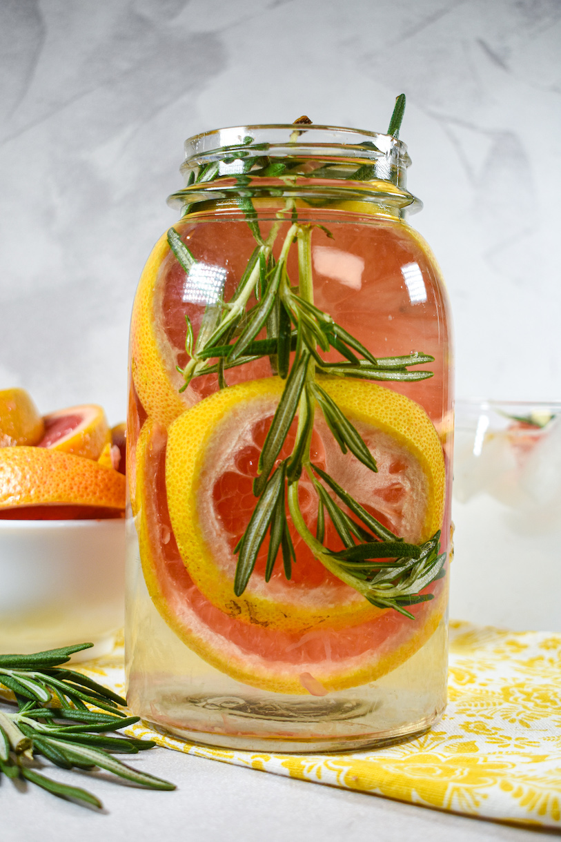 a jar of water with grapefruit slices and rosemary