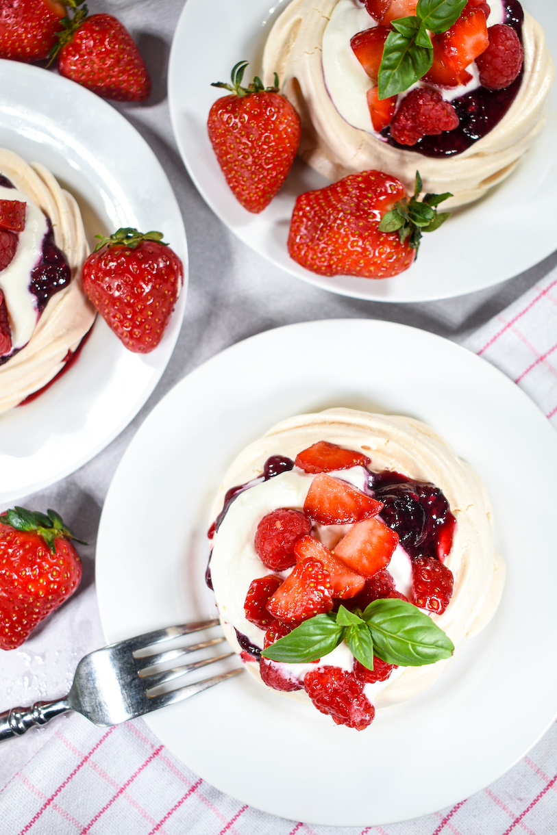 Plates of miniature pavlovas surrounded by fresh strawberries