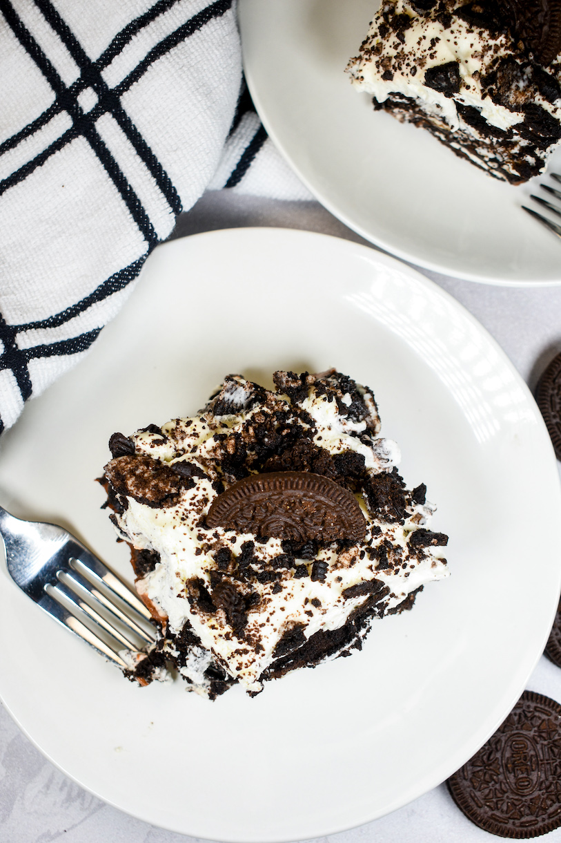 Looking down at a slice of Oreo icebox cake on a white plate with a fork