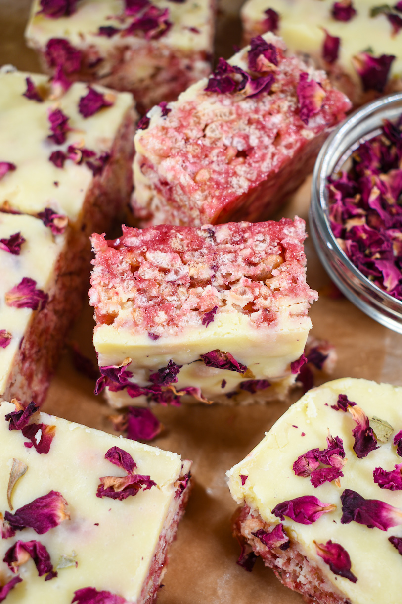 pink rice krispie treats and dish of rose petals on a sheet of parchment