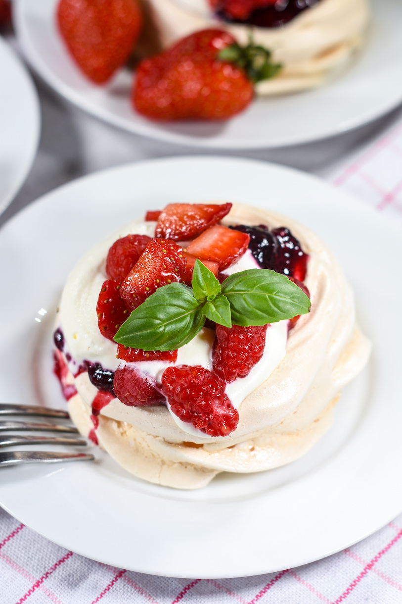 Closeup of a mini pavlova on a white plate with a fork